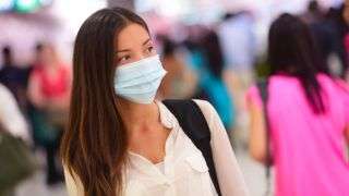woman in crowded space wearing surgical mask