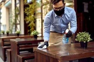A worker disinfecting tables at a restaurant. 