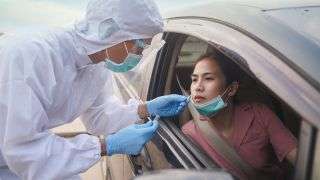 A woman getting a COVID-19 test at a drive-up testing site.