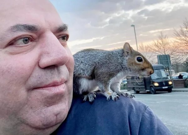 Mehmet Onal with a squirrel he rescued sitting on his shoulder.