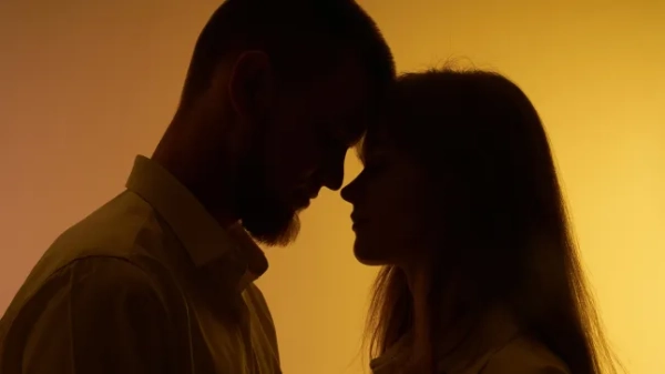 Pair in silhouette on yellow background.